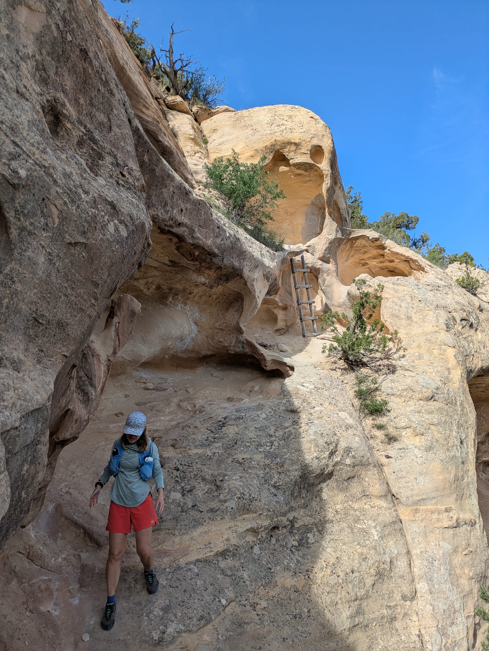 Heidi walking down slick rock w/a ladder in the background that allowed us to drop down a level